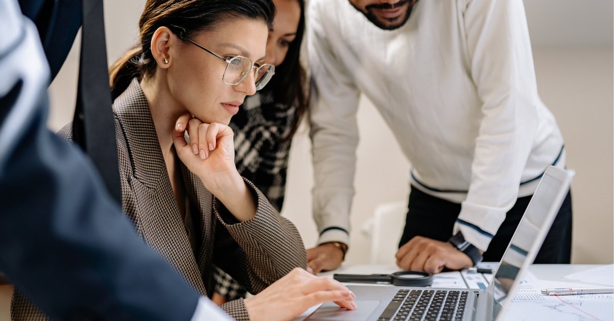 Tres compañeros de trabajo revisando información juntos en la pantalla de un portátil