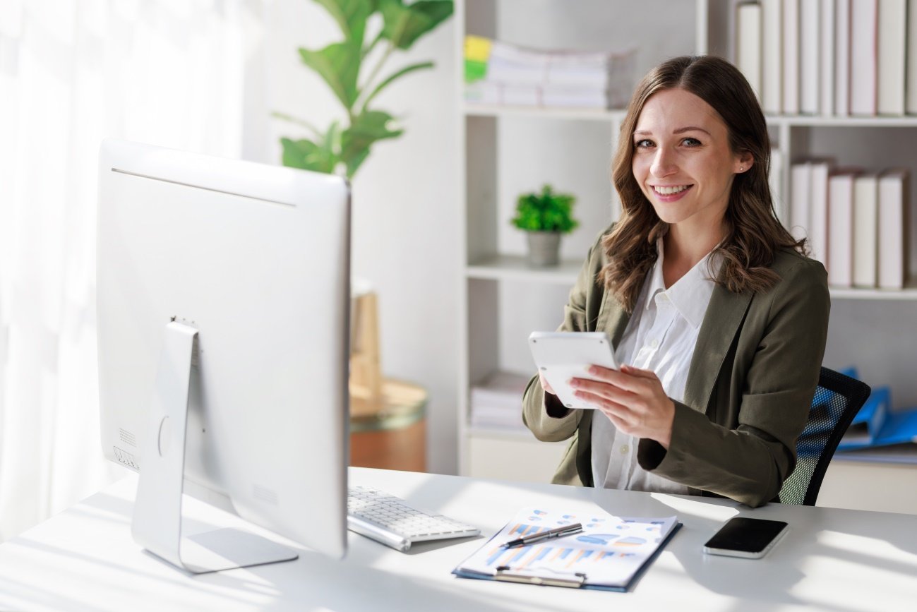 Profesional sonriente con una tablet junto a gráficos de datos sobre su mesa de trabajo